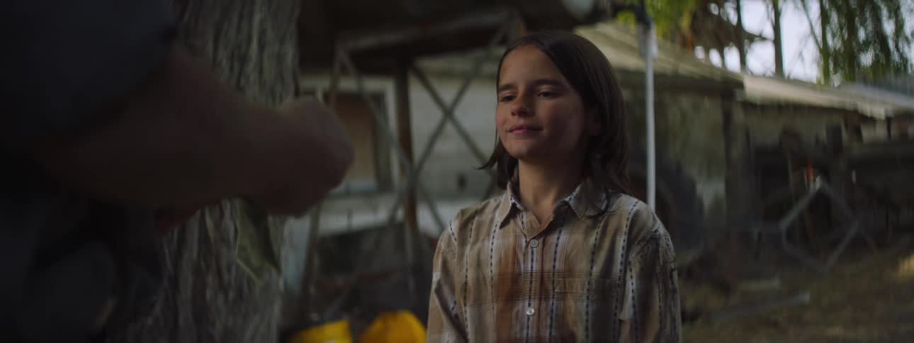 A little girl stands watching a person count money and then hand it to her