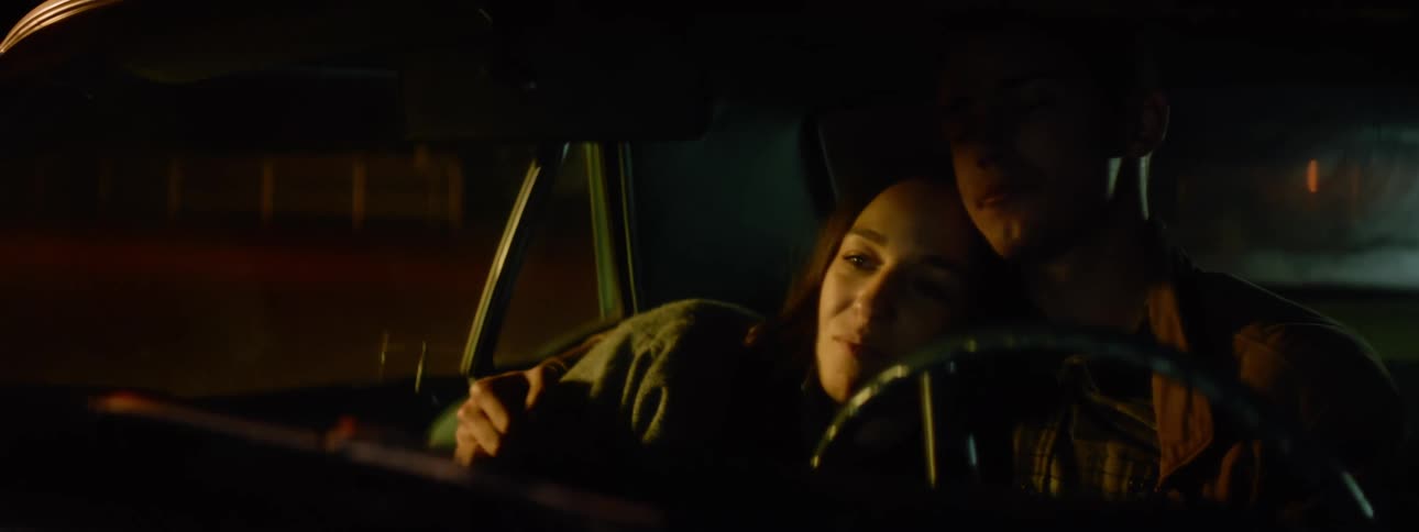 Couple cuddle together in car front seat while snacking