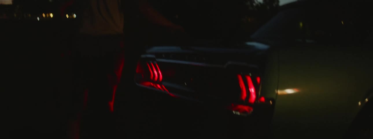 Man closes car trunk at dusk in the countryside