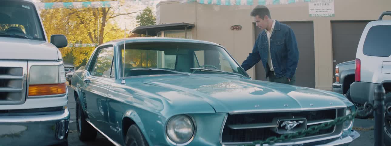 A man stops to check out a classic mustang at a car dealership