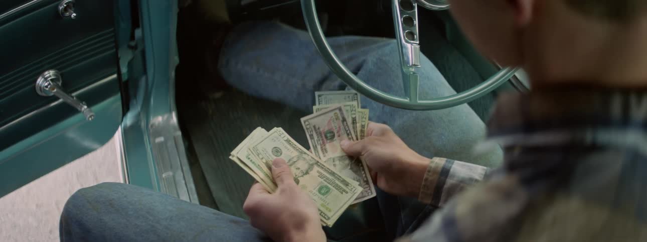 A man sitting in a car counting money