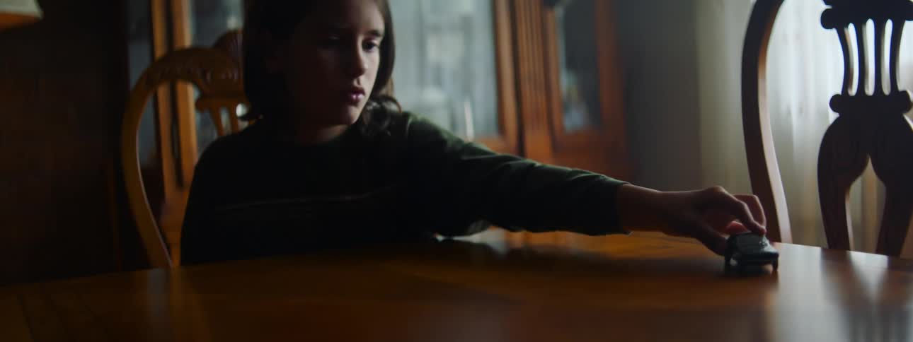 Youth sitting at dining table plays with a toy car