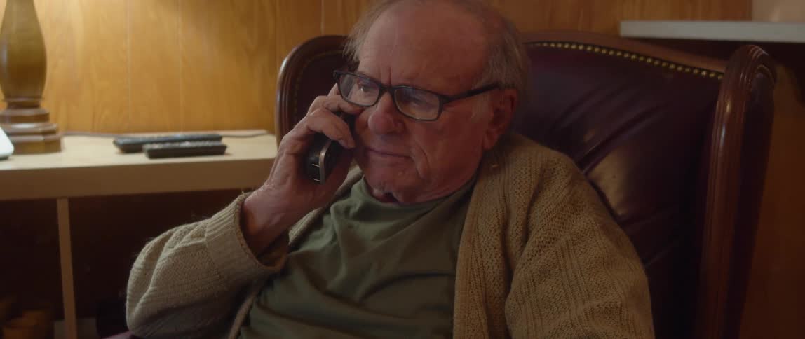 A man is sitting on a chair and talking on the phone