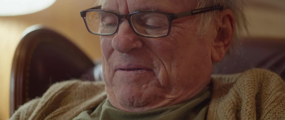 Old man puts on reading glasses and starts reading a funny book smiling and laughing