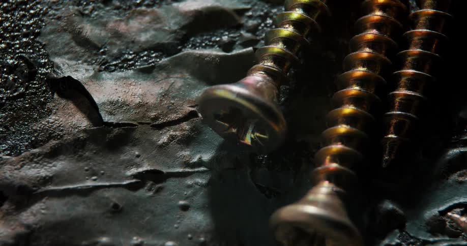 Screws lying on peeling surface as light brightens then fades