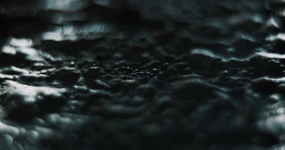 Extreme closeup of dried gray paint on asphalt bubbling and moving with light and shadow