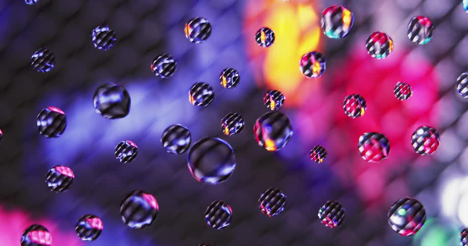 Water droplets sit on clear glass as colored lights move in the distance reflecting texture on the spheres