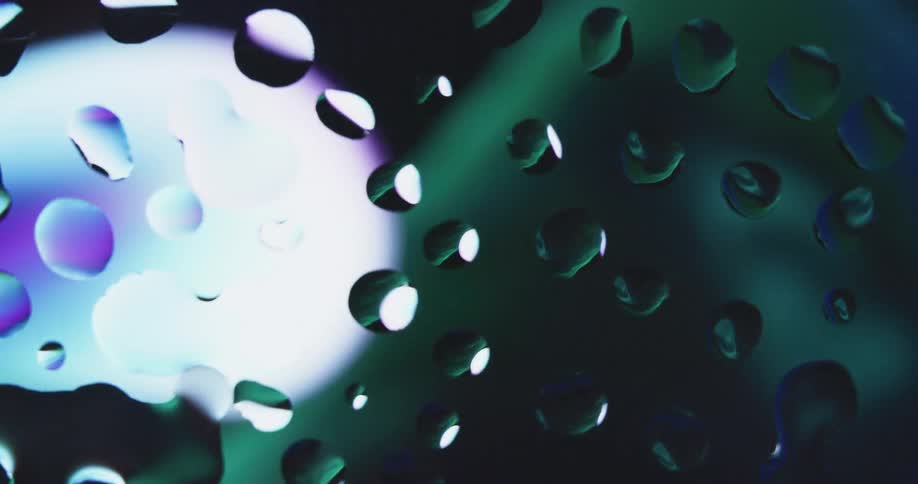 Water droplets on glass reflecting colors and lights