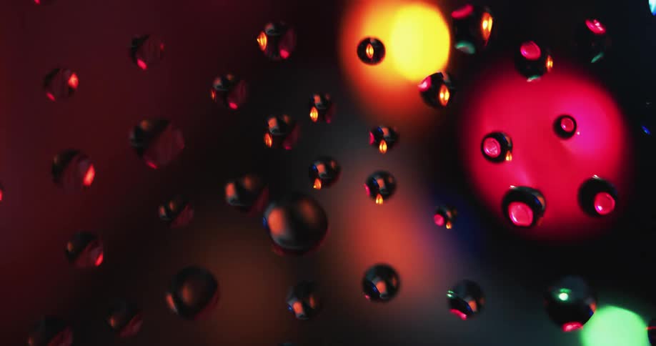 Water droplets on a glass reflecting lights spinning around