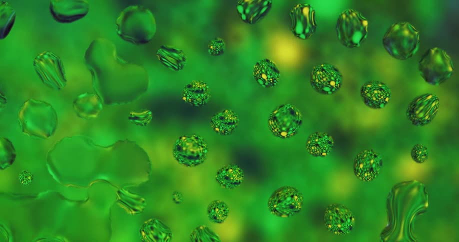 Water droplets sit on clear glass as green and yellow light move behind them reflecting color in the droplets