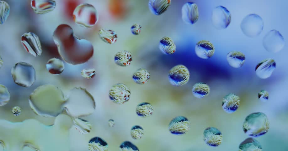 Water droplets sit on clear glass as colored lights move in the distance reflecting on the drops