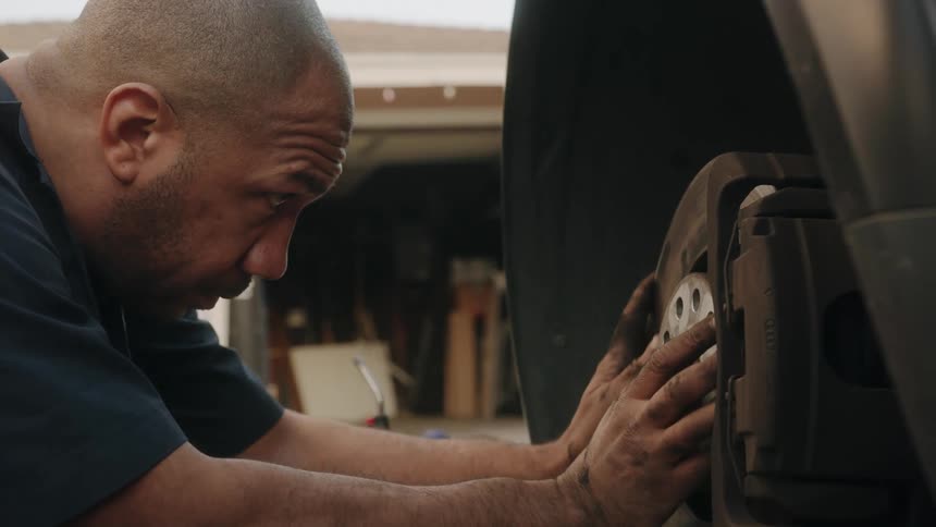 Mechanic with stained hands works to adjust machine
