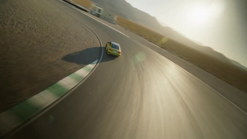 A car travels around a curve on a racing track in the desert during the day