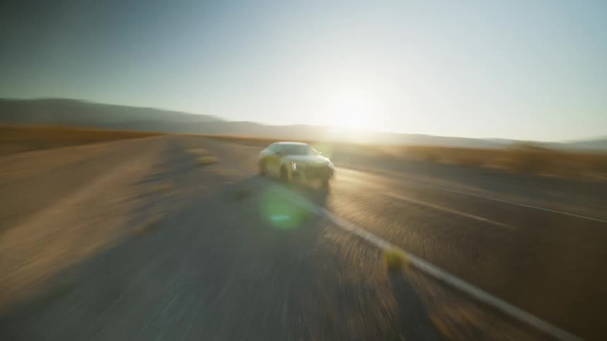 The camera zooms past a yellow car driving down the road and turns all the way around at the end