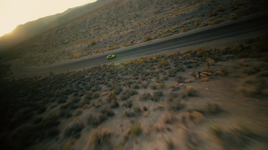 A car travels along a road through a vast countryside during the day