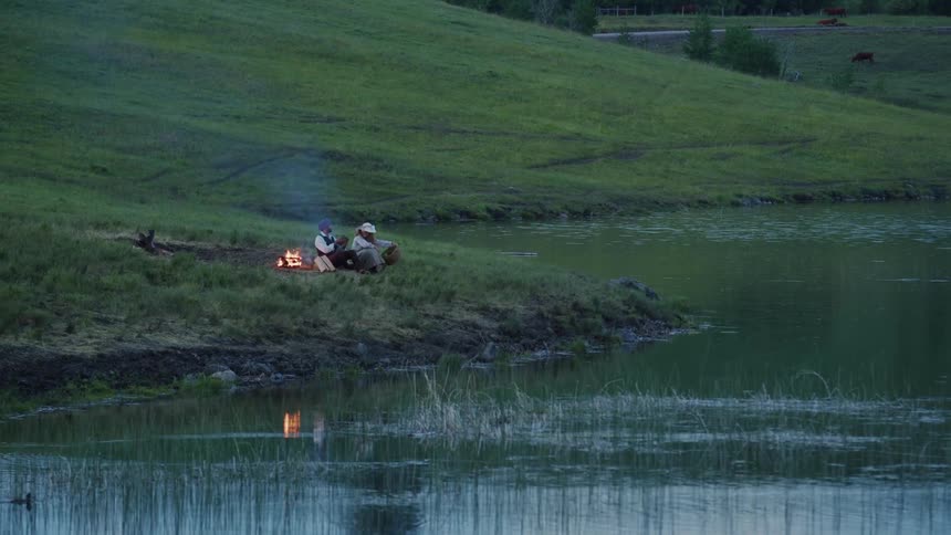 Two people sit by the campfire
