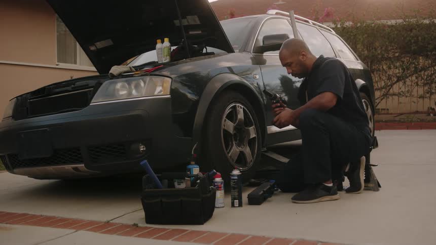 A man works under the hood of his vehicle at home