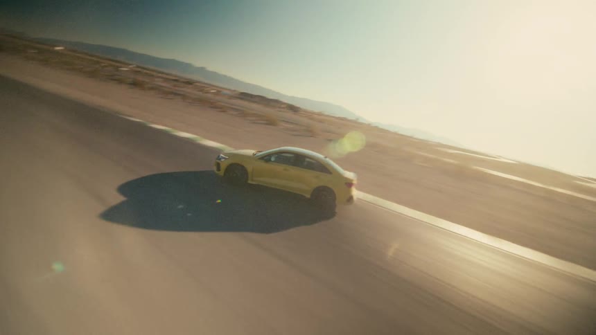 Dynamic aerial drone shot of a yellow sports car driving on a race track on the desert at sunset