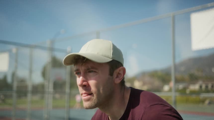 Man focuses while waiting on tennis court with mountain in the background