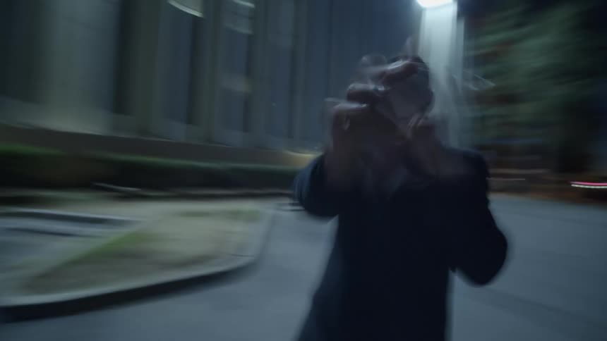 A man is outside in front of a white building throwing punches in the air while moving in circles in fast motion