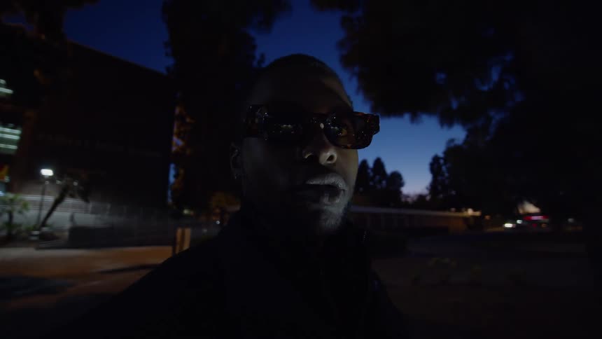 A close up of a mans face wearing glasses with light flashing across his face