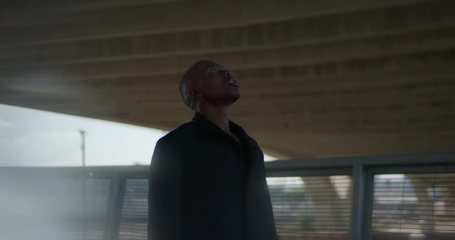 Man standing under overpass looks up at underneath portion of it