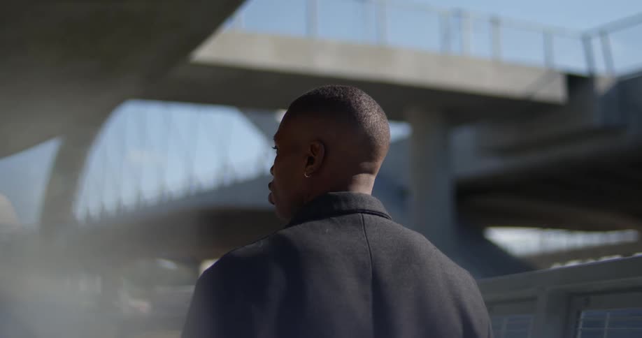 Man looks around while walking under overpasses connected with a bridge