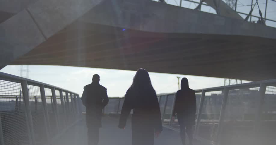 Three people walking on an overpass