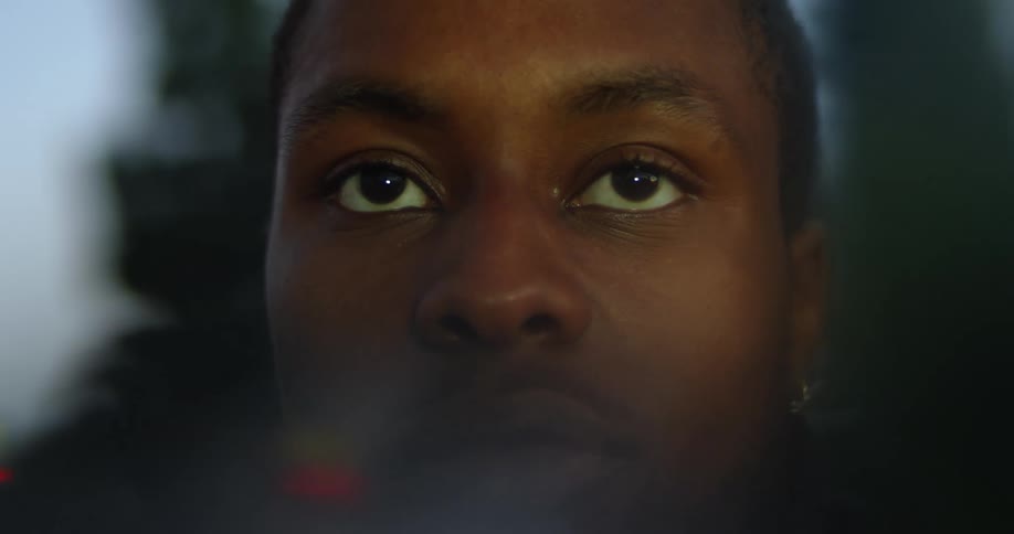 Clear surface reflects car lights as man looks through it