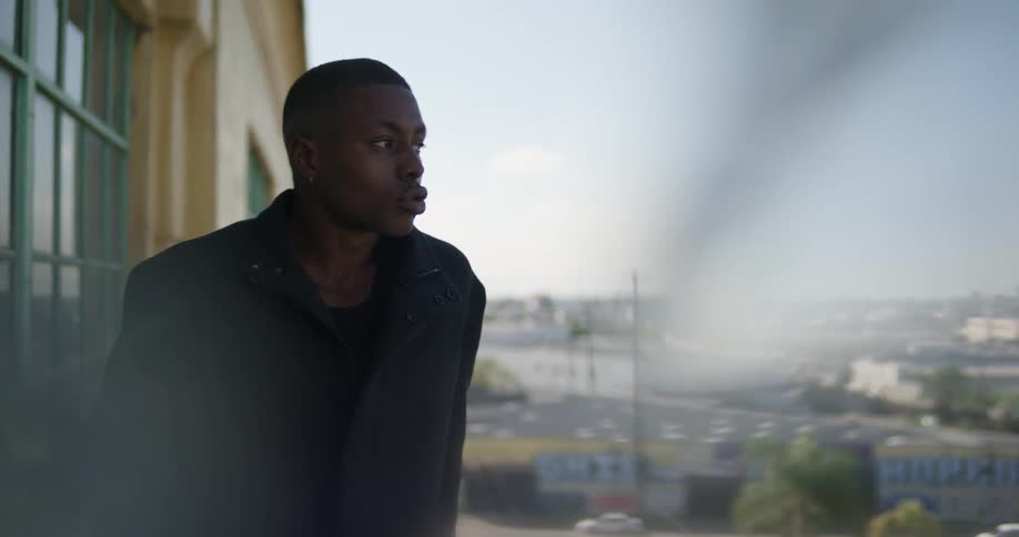 A man looks out over a city from the balcony of a building