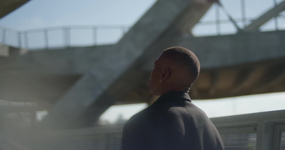 A man looks around while standing on a pedestrian bridge