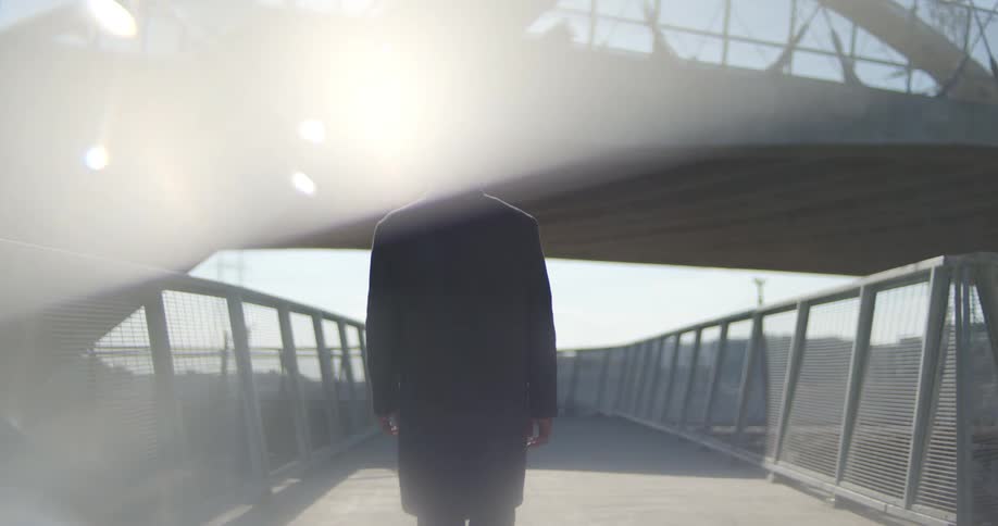 A man walks along a pedestrian bridge near downtown