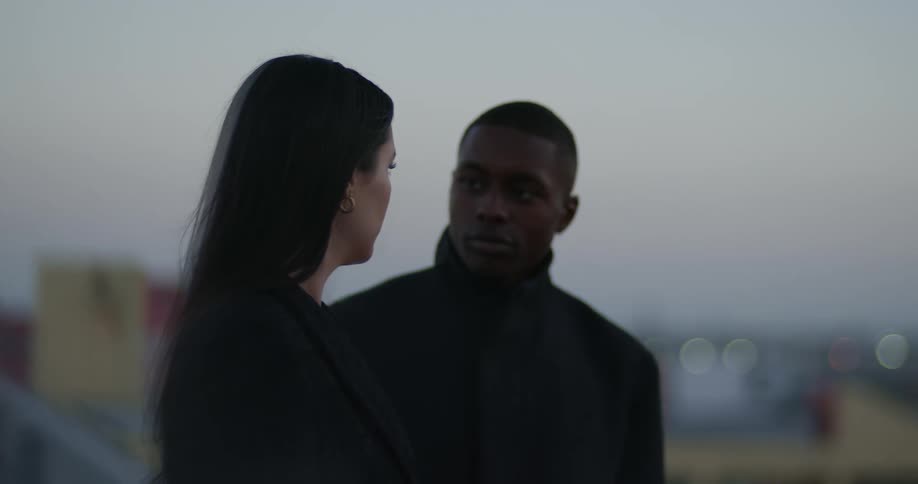 Man focuses on woman as he moves closer with town in the background