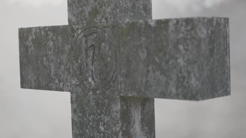 A stone cross standing in a foggy setting
