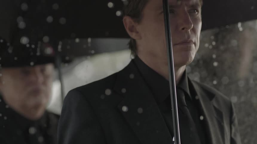 Rain falls on a man in black
