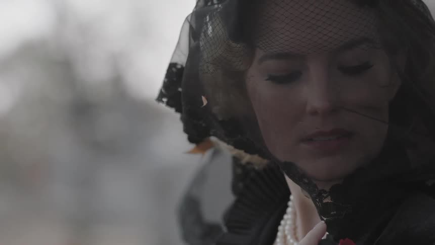 A woman is standing in the wind with a veil on