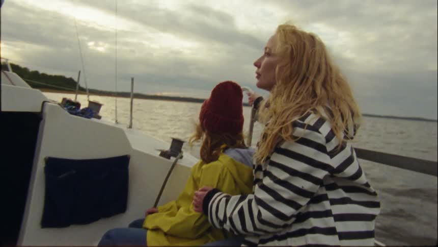 Mother and daughter on a boat in the ocean about a mile off the coast mother rubs daughters shoulder as they enjoy the breeze