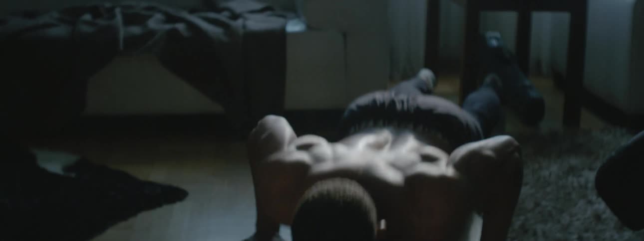 Man does push ups at home in dimly lit room