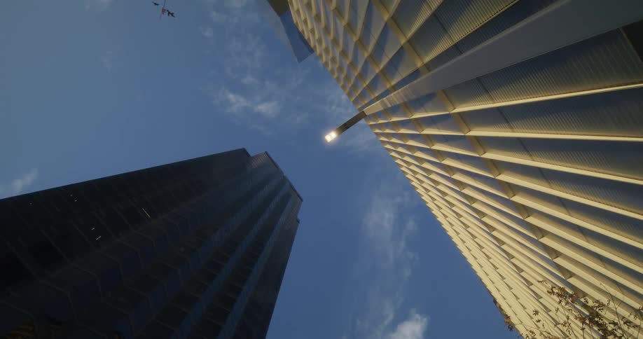 Twisting footage of the blue sky over tall buildings in the city at morning