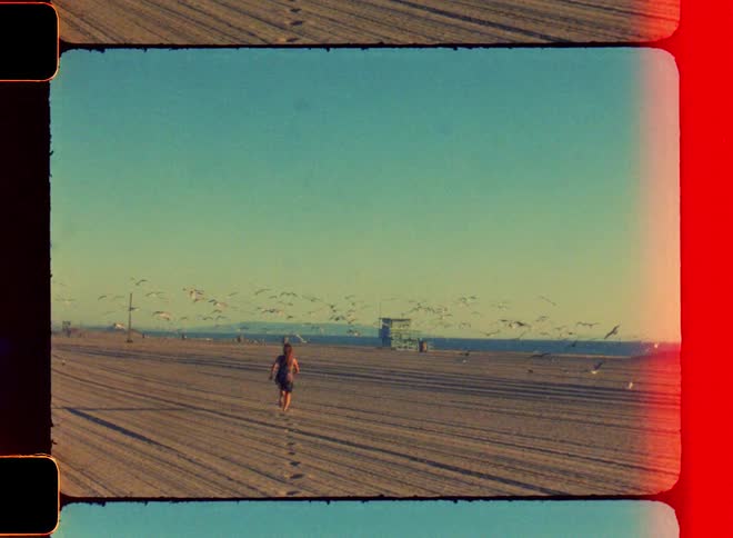 A woman is running towards the beach while the sun is setting
