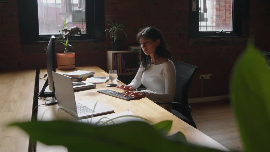 A young woman is in a office working and on her computer
