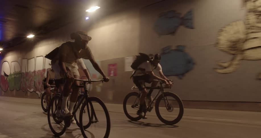 A group of cyclist ride together along a road through a tunnel