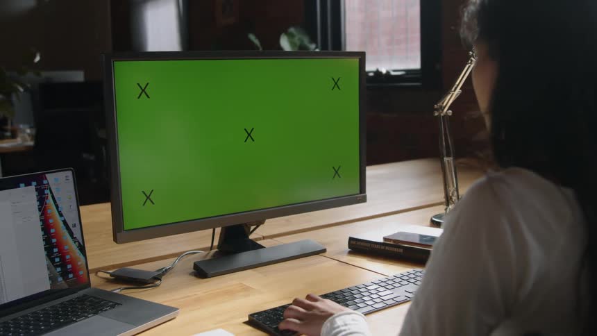 A woman is sitting at a desk and typing on a computer