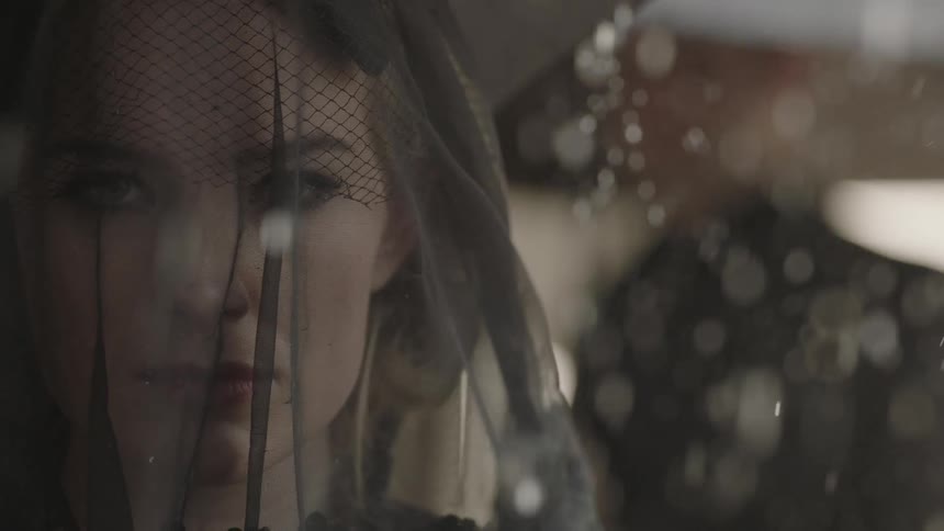 Woman wearing a black veil as the rain comes down