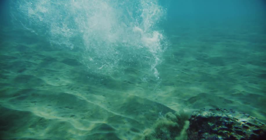 Rock sinks in water as the sun shines brightly