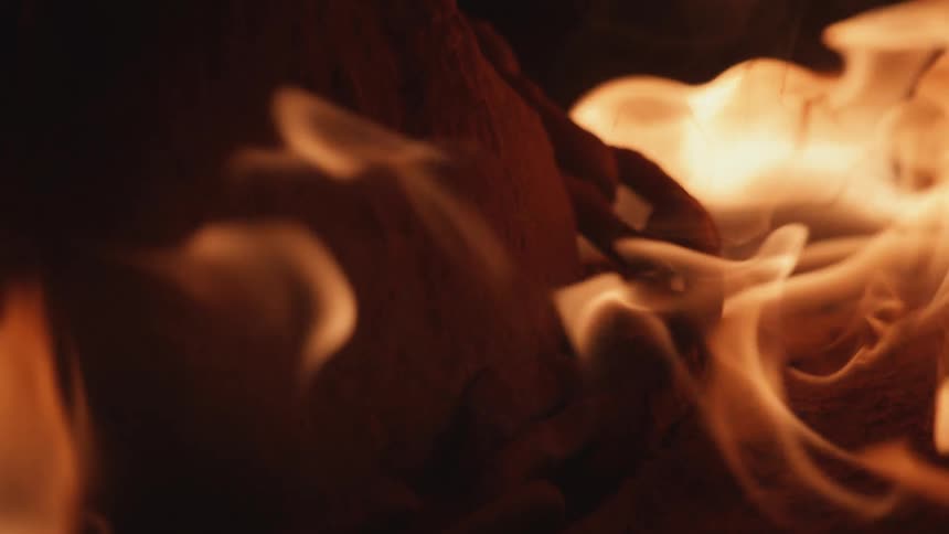 Close up of orange flames engulfing a chain wrapped around a rock