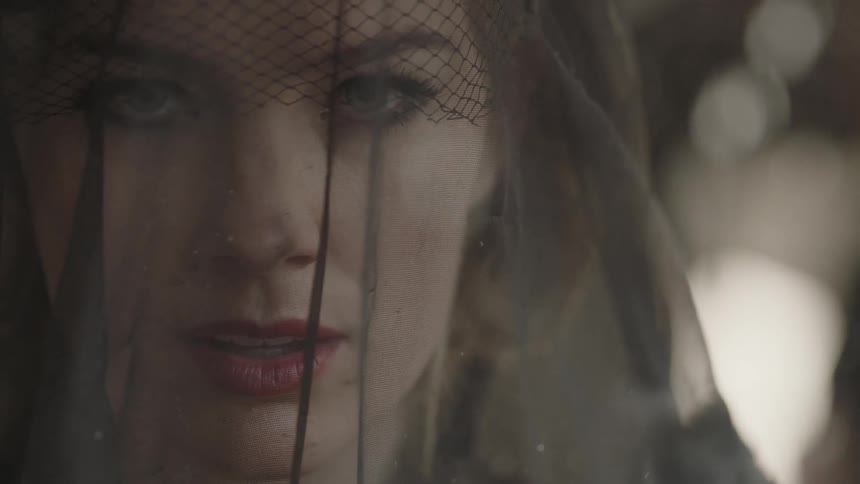 A woman wearing a lace hat mourns on a rainy day