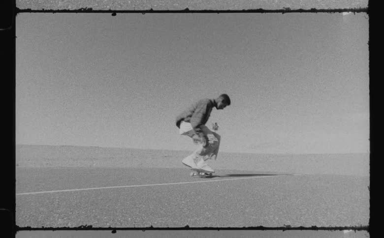 A male is skateboarding on tarmac outdoors