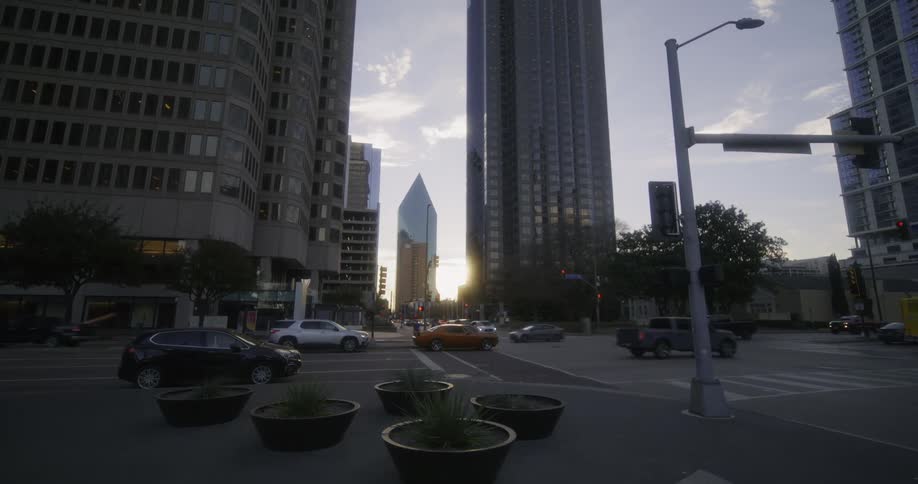 Downtown area with intersection vehicles and high rise buildings at sunset