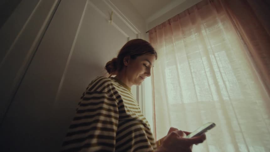 A woman is smiling and texting on her cellphone